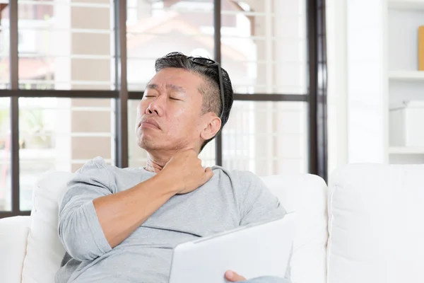 Reife asiatische Mann Schulterschmerzen, während mit Tablet-Computer — Stockfoto