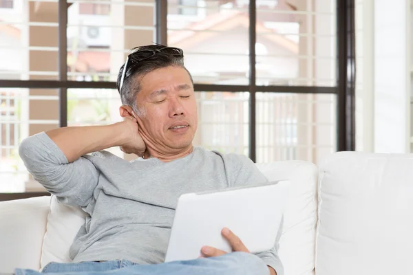 Mature Asian man neck pain while using tablet computer — Zdjęcie stockowe