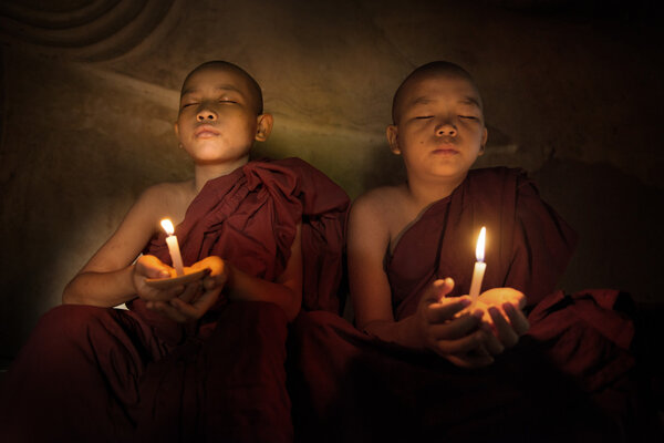 Buddhist novices praying with candlelight