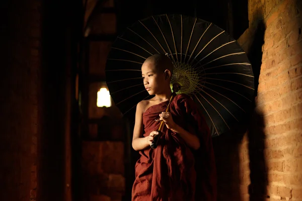 Buddhist novice walking with umbrella — Stock Photo, Image