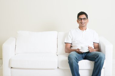 Kanepede oturan ve kahve içme Asyalı adam