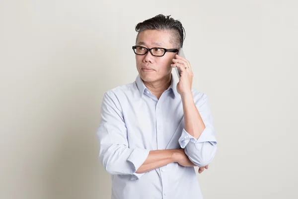 Mature Asian man calling on smartphone — Stockfoto