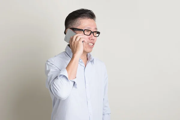 Зрелый азиат звонит на смартфон — стоковое фото