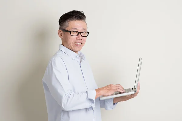 Mature Asian man using pc notebook — Stockfoto