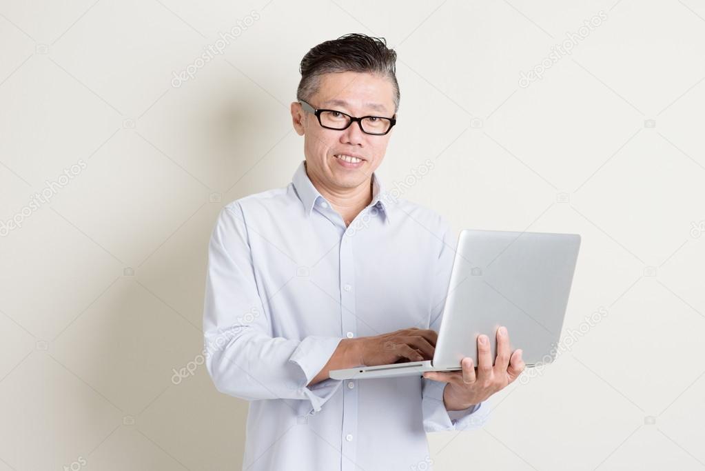 Mature Asian man using laptop computer