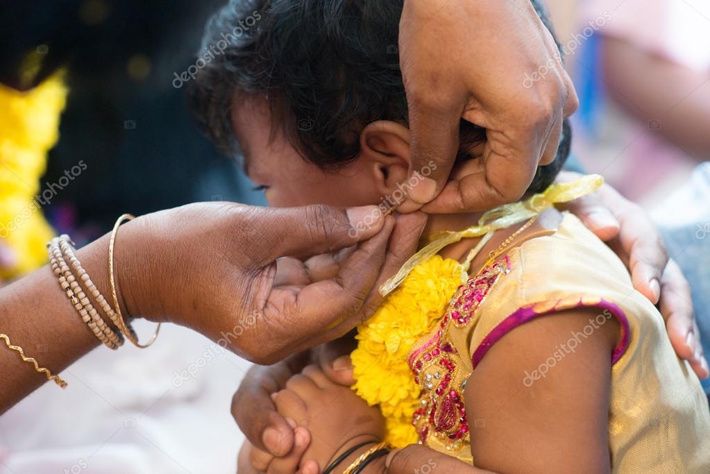 Baby girl in ear piercing ceremony Stock Photo by ©szefei 97296656