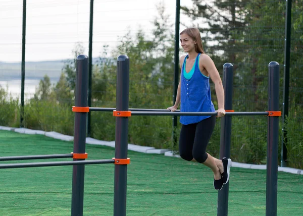 Fille en vêtements de sport poussé sur les barres — Photo