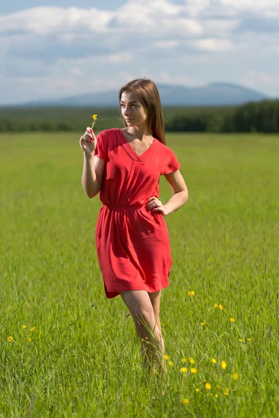 20-jähriges Mädchen in einem roten Kleid mit einer gelben Blume — Stockfoto