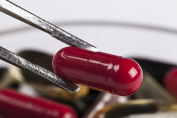 Pincers with red pill — Stock Photo, Image