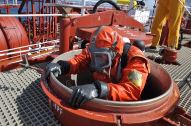 man in chemical suit entering inside cargo tank on chemical tanker for cleaning operation clipart