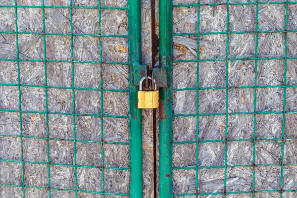 メッシュワイヤーゲートでロックされた真鍮南京錠 — ストック写真