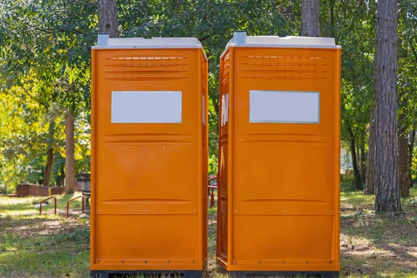 Två Orangefärgade Portabla Toalettstugor Stadsparken — Stockfoto