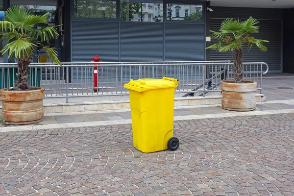 Желтый пластиковый мусорный бак — стоковое фото