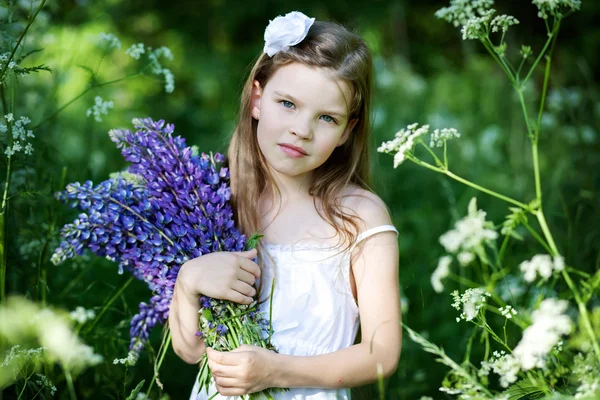 Красивая маленькая девочка с фиолетовыми волчанками на открытом воздухе — стоковое фото