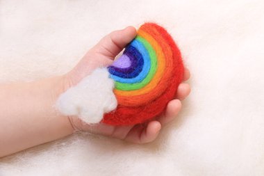 Bir bebeğin eli küçük bir gökkuşağını tutuyor..