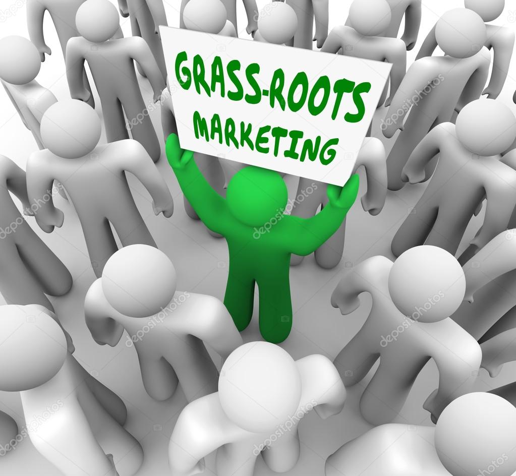 A man holding a Grass Roots Marketing sign in a crowd