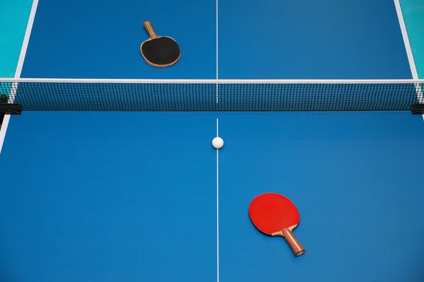 球拍和球在乒乓球桌上 图库照片