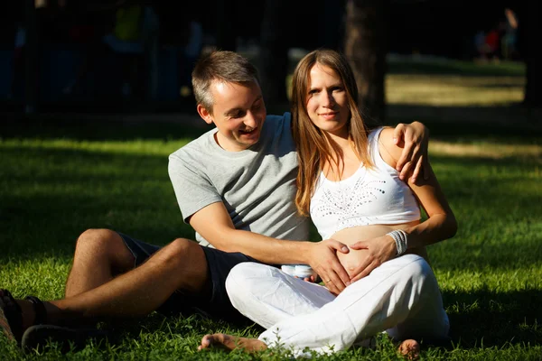 Mujer embarazada y su marido tomados de la mano en forma de corazón sobre su vientre . — Foto de Stock