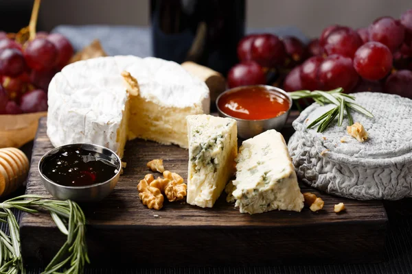 Cheese plate served with wine, jam and honey — Stock Photo, Image