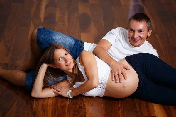 Mujer embarazada feliz con su marido acostado en el suelo — Foto de Stock