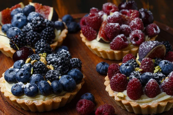 A friss bogyós gyümölcsök a fa háttér tartlets — Stock Fotó