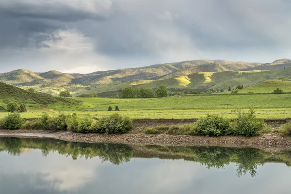 Lac et prairies verdoyantes aux contreforts — Photo