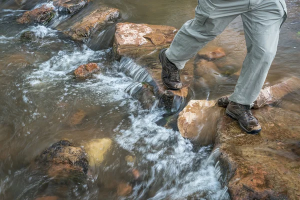 Hiker crossing mountain creek — Stock Photo, Image