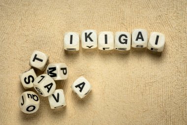 ikigai word abstract in wooden letter cubes against handmade bark paper, Japanese lifestyle concept  - a reason for being as a balance between love, skills, needs and money clipart