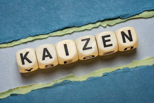 kaizen word abstract in wooden letter cubes against paper abstract in green tones,  Japanese continuous improvement and a change for better concept