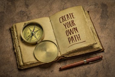 create your own path - handwriting in an antique leather-bound journal with a stylish pen and vintage brass compass, lifestyle, career and personal development concept clipart