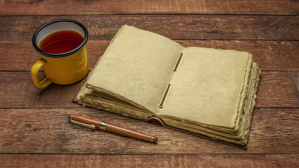 アンティーク レザーバインド ジャーナル紙のページとお茶を入れた素朴な木のテーブルの上のスタイリッシュなペン ジャーナリングコンセプト — ストック写真