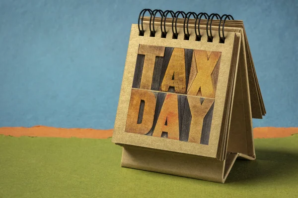 tax day word abstract - text in vintage letterpress wood type in a spiral  desktop calendar - business  financial concept or reminder