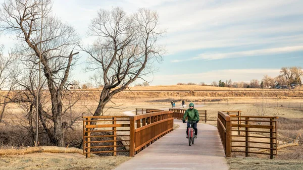 コロラド北部のフォートコリンズで雪のない冬や秋の典型的な風景の中に新しく建設された自転車道を成熟した男性サイクリストと歩行者 — ストック写真