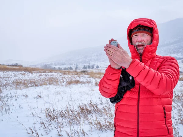 cold senior male hiker with a pocket electric hand warmer - Lory State Park in northern Colorado in winter scenery