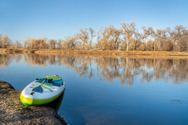 İlkbaharın başlarında bir gölün üzerinde şişirilebilir bir kürek çekme tahtası Prospect Göletleri, Fort Collins, Colorado 'daki Poudre Nehri boyunca yer alan doğa alanlarından biri.