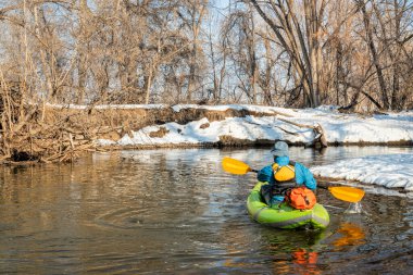 Yaşlı erkek kürekçi, Fort Collins, Colorado 'daki Poudre Nehri' nde küçük bir nehirde şişme su kayağı yapıyor.