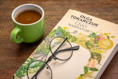 Fort Collins, CO, ABD - 20 Mart 2021: The Tender Narrator (Polonya baskısı), Olga Tokarczuk 'un kahve ve okuma gözlükleriyle yazdığı son kitap - 2018 Nobel Edebiyat Ödülü.