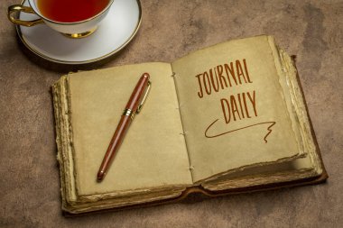 journal daily inspirational advice - handwriting in an antique leather-bound journal with decked edge handmade paper pages with a stylish pen and cup of tea against handmade paper, journaling concept clipart