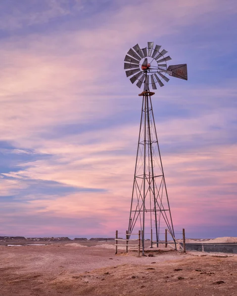 windmill with a pump and cattle water tank in shortgrass prairie, Pawnee National Grassland in northern Colorado, winter or early spring scenery