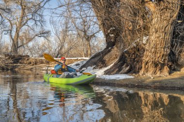 Yaşlı erkek kürekçi, Fort Collins, Colorado 'daki Poudre Nehri' nde küçük bir nehirde şişme su kayağı yapıyor.