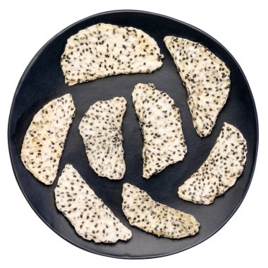 İzole edilmiş siyah seramik tabakta kurutulmuş beyaz ejderha meyvesi (pitaya) dilimleri