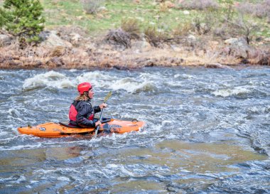 Fort Collins, CO, ABD - 30 Nisan 2021: Genç erkek kanocu bahar başlarında Poudre Nehri 'nde kürek çekme sezonunun başında hızlı koşuyor.