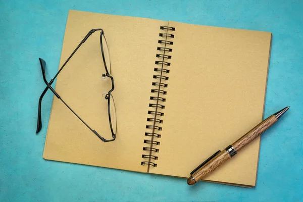 Leeres Spiralkunstskizzenbuch Mit Stift Und Lesebrille Gegen Blaues Strukturiertes Papier — Stockfoto