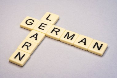 Sarı desenli kağıda karşı fildişi harf karolarında Almanca bulmaca öğrenin