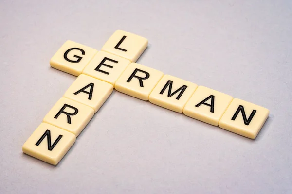 learn German crossword in ivory letter tiles against yellow textured  paper
