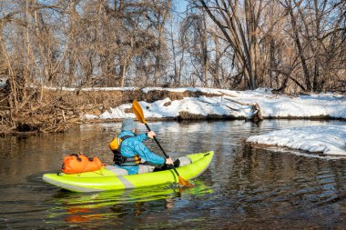 Yaşlı erkek kürekçi, Fort Collins, Colorado 'daki Poudre Nehri' nde küçük bir nehirde şişme su kayağı yapıyor.