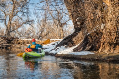 Erkek kürekçi, Fort Collins, Colorado 'daki Poudre Nehri' nde küçük bir nehirde şişme su kayağı yapıyor.
