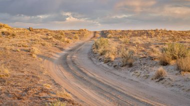 Gün batımında çölde kumlu bir yol, San Rafael Swell bölgesi, Utah.