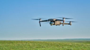 New Raymer, CO, USA - June 8, 2021:  Radio controlled DJI Mavic 2 Pro quadcopter drone is flying over green prairie. clipart