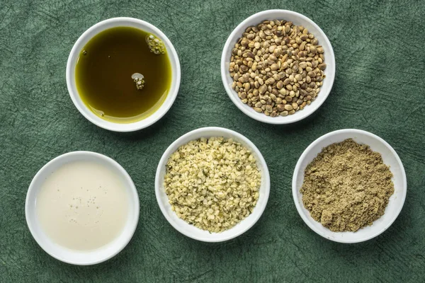 收集大麻种子产品 蛋白质粉 牛奶和小白碗中的油与绿纸的对比 超级食品概念 — 图库照片